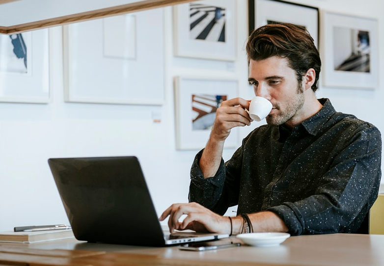 man drinking coffee and using laptop